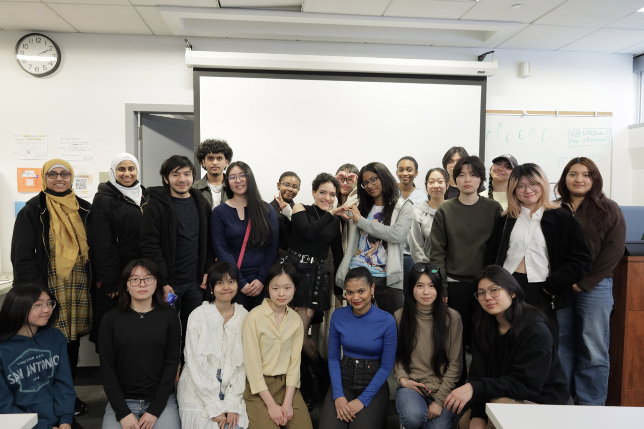 Twenty-three students pose for a group photo in the NMA Studio.